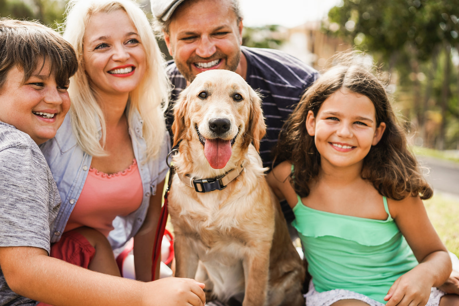 A happy family with their family dog smiling for a photo. Honoring your loved pets with cremation jewelry is a beautiful way of honoring them.