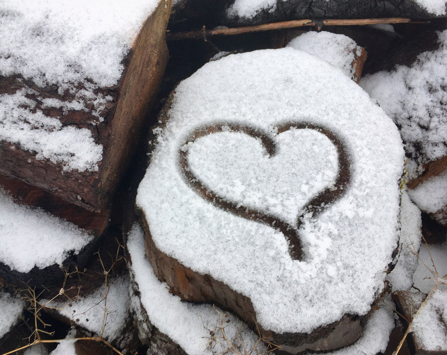 Picture of a heart drawn in some snow on top of some wood
